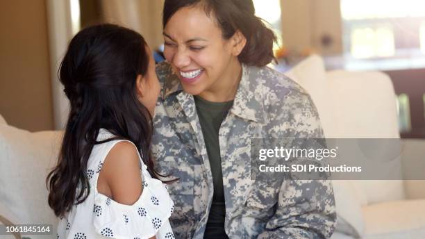 mutter in uniform und tochter sehen und einander anlächeln - smile woman child stock-fotos und bilder