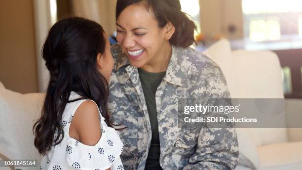 moeder in uniform en dochter kijken en lachen naar elkaar - smile woman child stockfoto's en -beelden