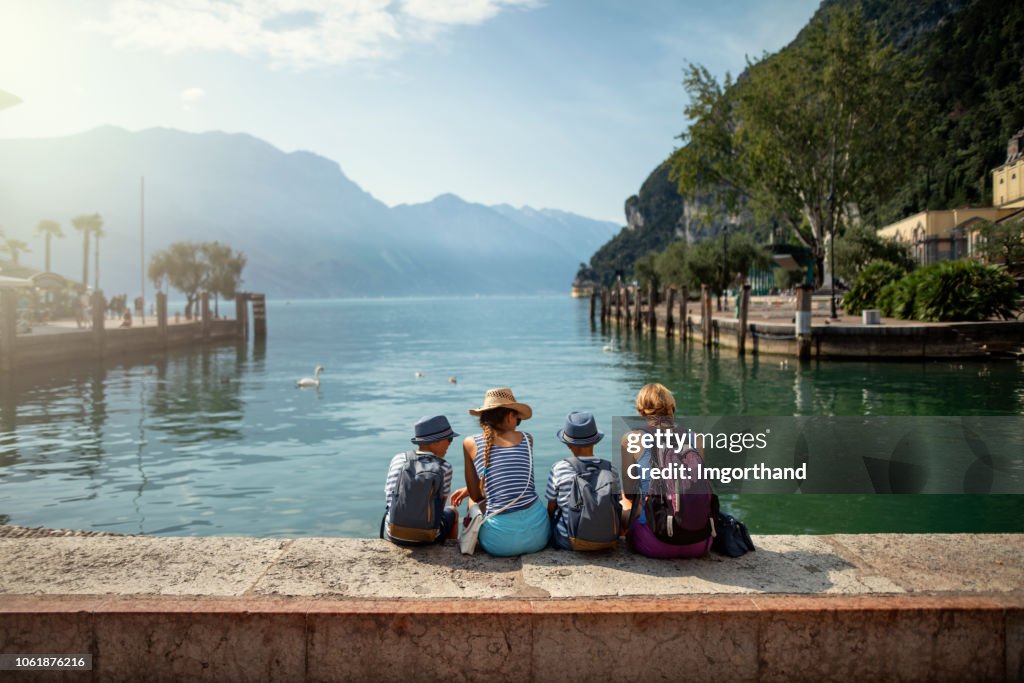 Familie sitzen im Hafen von Riva del Garda und genießen die Aussicht auf den Gardasee