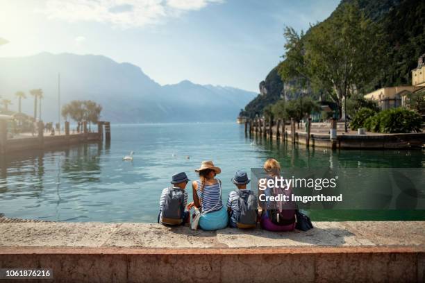 family sitting in harbor of riva del garda and enjoying view of lake garda - riva del garda stock pictures, royalty-free photos & images
