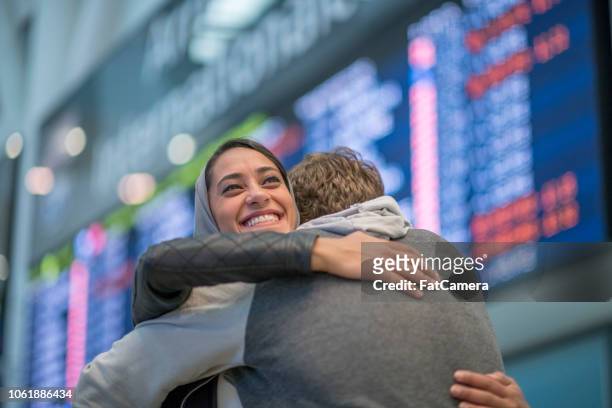 a warm embrace at the airport - arrivals stock pictures, royalty-free photos & images