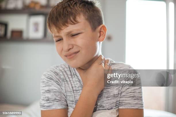 mal di gola - ragazzo che tiene il collo nel dolore - mal di gola foto e immagini stock
