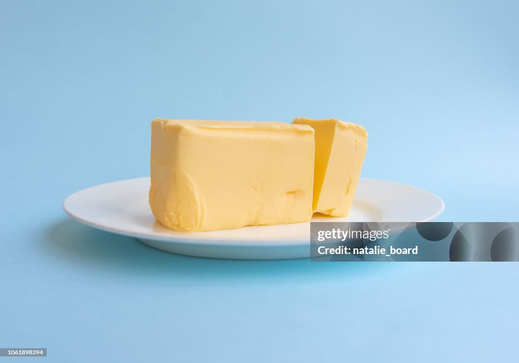 Organic butter on white plate against blue background