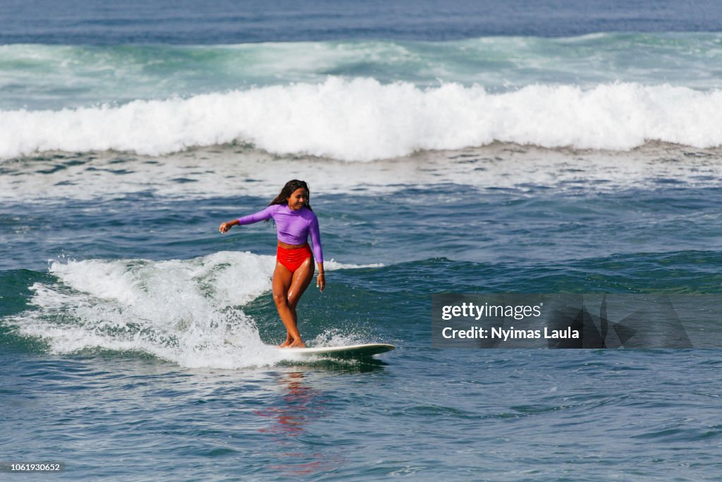 A dark skinned woman surfing