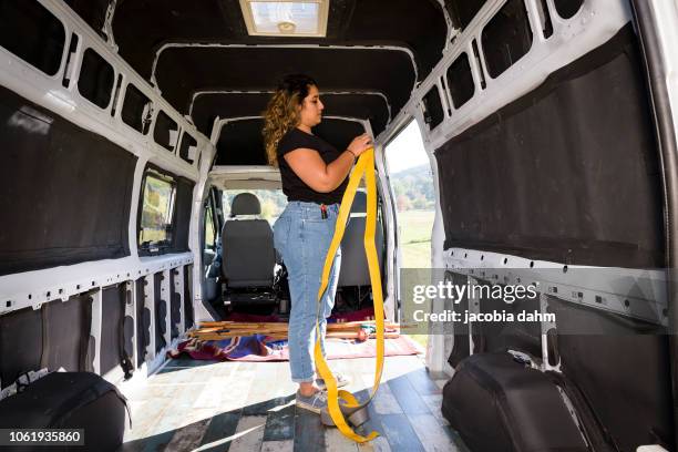 woman turning van into camper trailer, insulating inside of the car - trailer stock-fotos und bilder