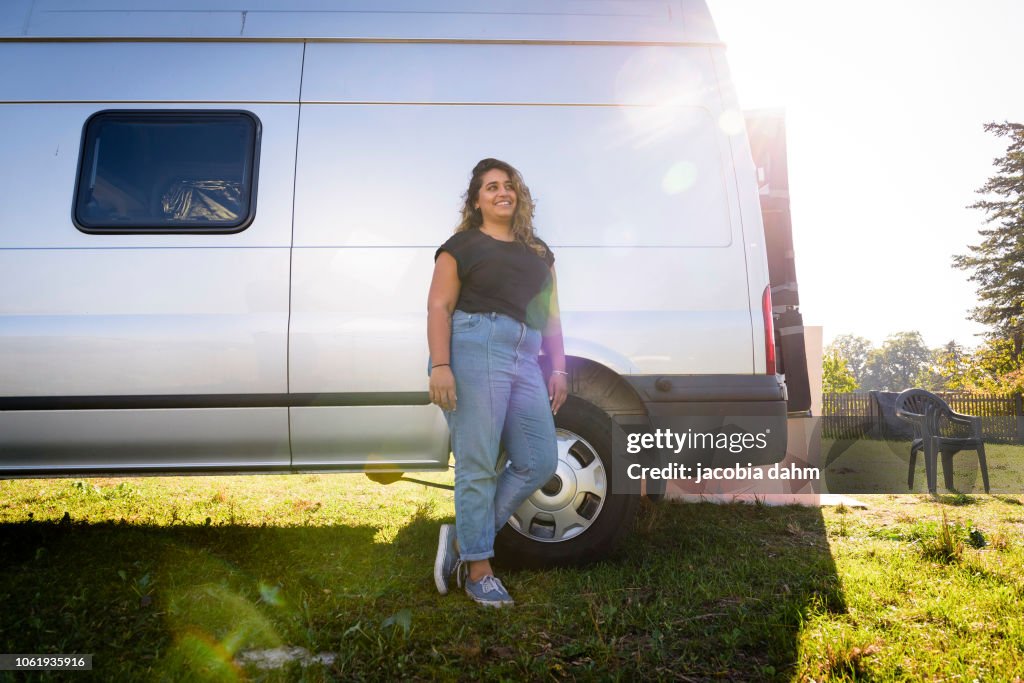 Woman turning van into camper trailer, posing for poirtrait