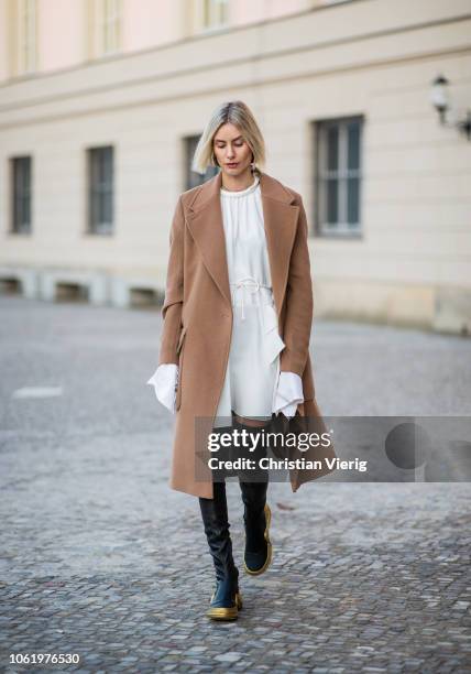 Lisa Hahnbueck is seen wearing white dress with wide sleeves, black overknees boots Louis Vuitton Cruise 2018, brown coat Baum und Pferdgarten on...