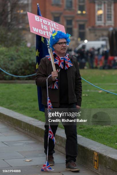 Carrying a placard asking if Brexit is worth it, a pro-EU remainer waks alongside College Green opposite the Houses of Parliament at a time of crisis...