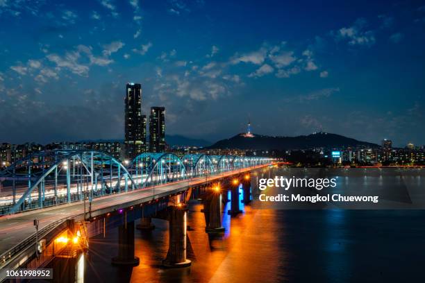 light trails of car driving on dongjak bridge cross over han river into n seoul tower at night in seoul city, south korea - han river stock pictures, royalty-free photos & images