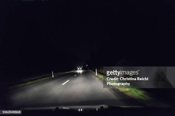 dark street at night with oncoming traffic - rear light car stock pictures, royalty-free photos & images