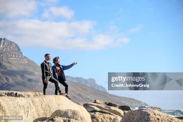 junge afrikanische paar blick auf das meer aus felsen - camps bay stock-fotos und bilder