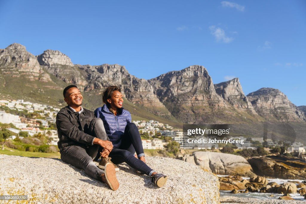 Two Laughing Rocks Happy African Young Couple Sit On Rocks Together Laughing High-Res ...