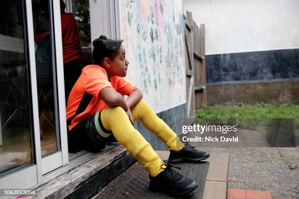 girl in football strip sitting on back doorstep and looking away - soccer back stock-fotos und bilder