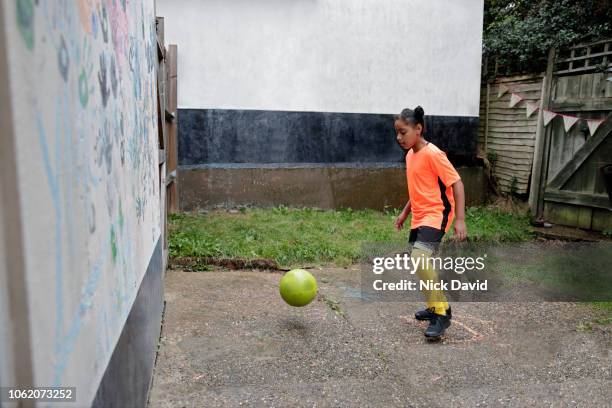 girl playing football in back garden against wall - girl kicking stock pictures, royalty-free photos & images