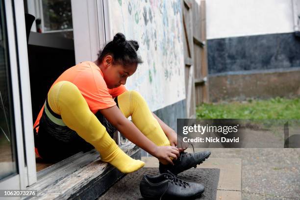 girl tying up her football  boot laces on back doorstep - soccer back stock-fotos und bilder