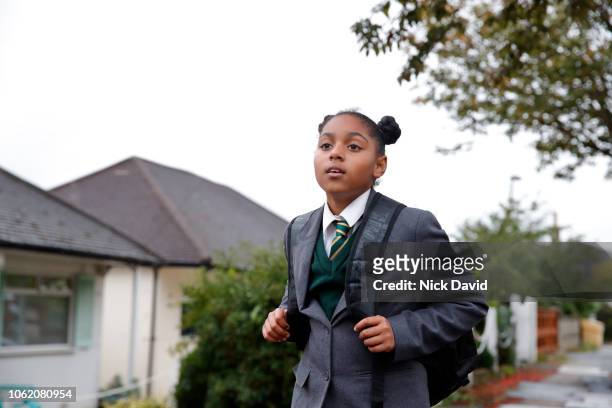 schoolgirl walking home wearing uniform and carrying backpack - school uniforms stock-fotos und bilder
