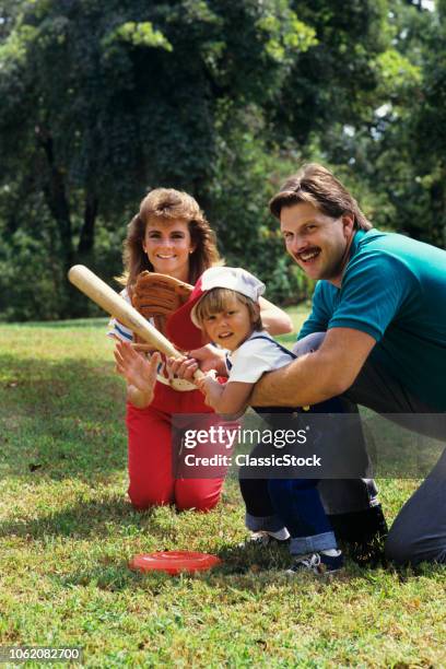 1980s PARENTS AND CHILD PLAYING BASEBALL IN BACKYARD