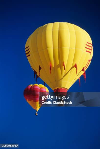 1990s RED AND YELLOW HOT AIR BALLOONS IN BLUE CLOUDLESS SKY