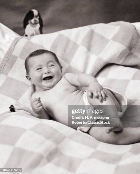 1920s HAPPY BABY POSED LYING ON SIDE WEARING CLOTH DIAPER TOY DOG ABOVE HER HEAD