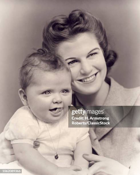 1940s SMILING MOTHER HUGGING SMILING TODDLER BABY DAUGHTER BOTH LOOKING OFF CAMERA