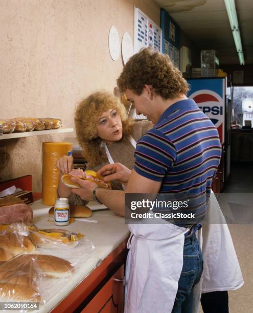 1980s TEENAGE BOY AND GIRL WEARING APRONS TALKING WORKING FLIRTING TOGETHER WORKING IN A SANDWICH SHOP