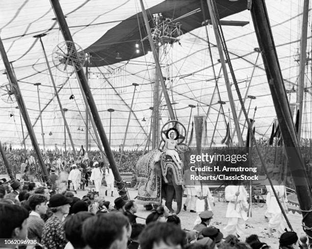 1930s 1940s 1950s INTERIOR OF BIG TOP CIRCUS TENT SHOWING AUDIENCE WATCHING PERFORMERS AND ELEPHANTS PARADE AROUND THREE RINGS
