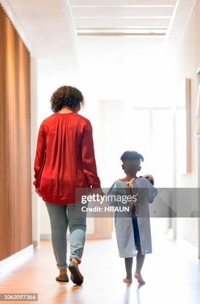 mother walking with ill boy in hospital corridor - childrens hospital stock pictures, royalty-free photos & images