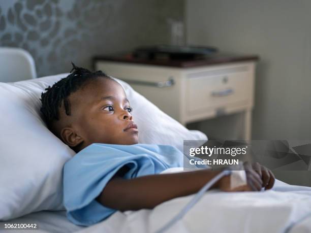 thoughtful ill boy lying on bed in hospital ward - hospital bed with iv stock pictures, royalty-free photos & images