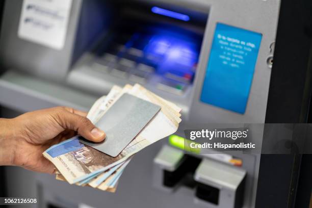 unrecognizable man holding his debit card and cash after withdrawing from atm - columbia stock pictures, royalty-free photos & images