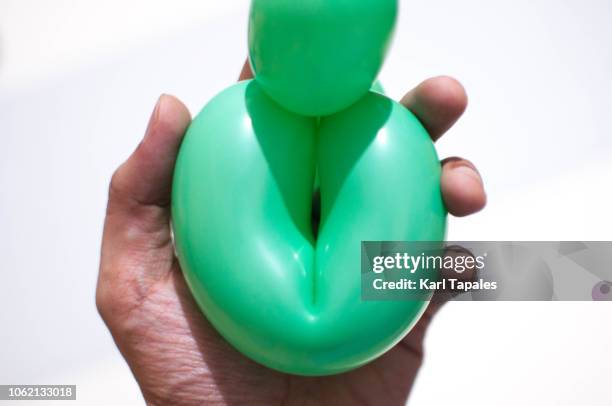 holding a green balloon against white background a concept of female vagina - schamlippen stock-fotos und bilder