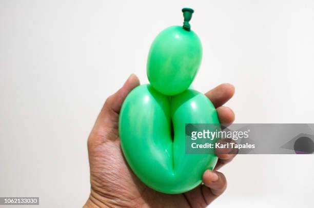 holding a green balloon against white background a concept of female vagina - schamlippen stock-fotos und bilder