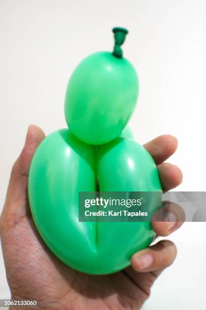 holding a green balloon against white background a concept of female vagina - schamlippen stock-fotos und bilder