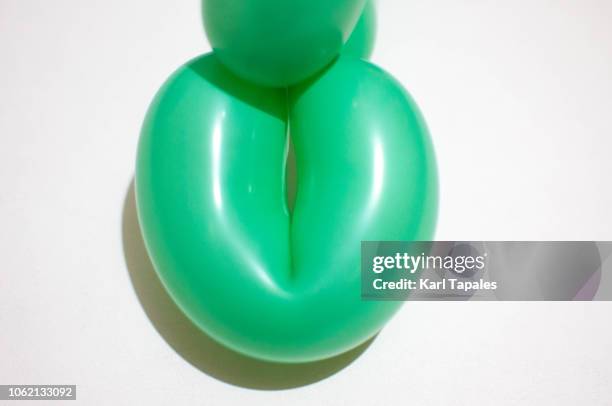 still life of a green balloon against white background a concept of female vagina - schamlippen stock-fotos und bilder