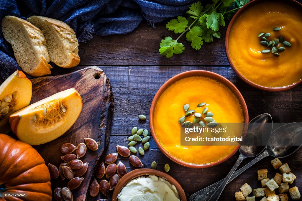 Pumpkin soup with ingredients on rustic wooden table