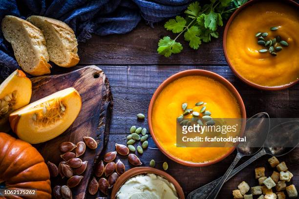 pumpkin soup with ingredients on rustic wooden table - soup stock pictures, royalty-free photos & images