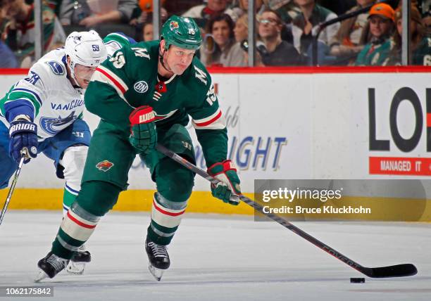 Matt Hendricks of the Minnesota Wild skates with the puck as Tim Schaller of the Vancouver Canucks gives chase during a game at Xcel Energy Center on...