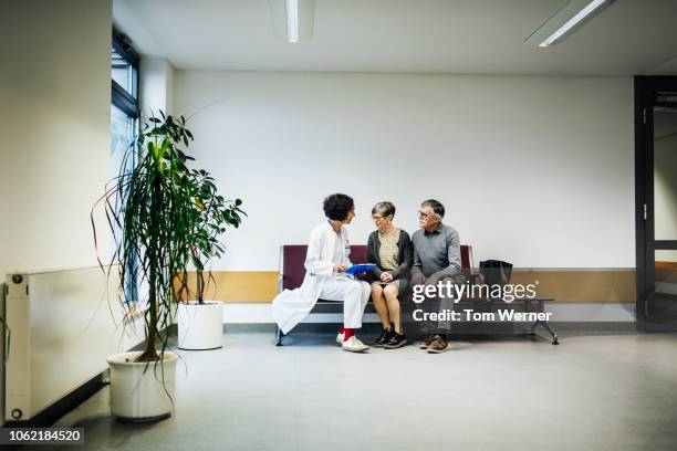 doctor talking to elderly couple - waiting room - fotografias e filmes do acervo