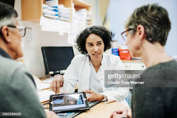 doctor explaining test results to couple - responsabilities experience advice photos et images de collection