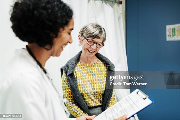 doctor going over test results with patient - doctor and patient talking photos et images de collection