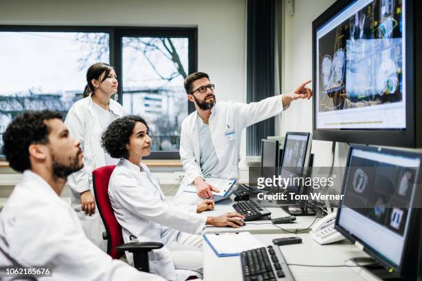 team of doctors looking at lab results - digital health display stockfoto's en -beelden
