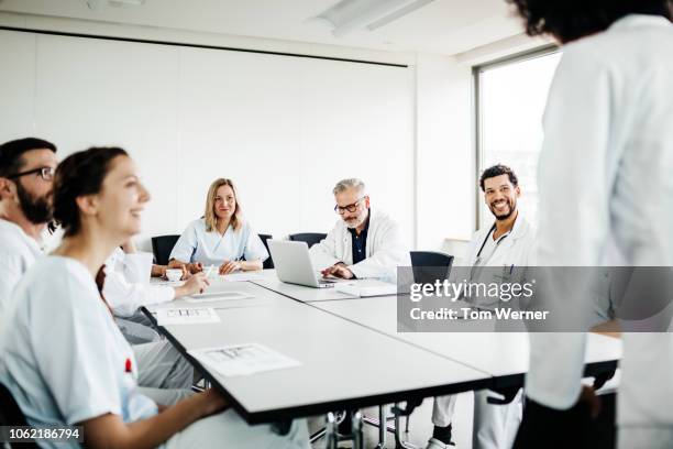 group of doctors meeting round table - mittelgroße personengruppe stock-fotos und bilder