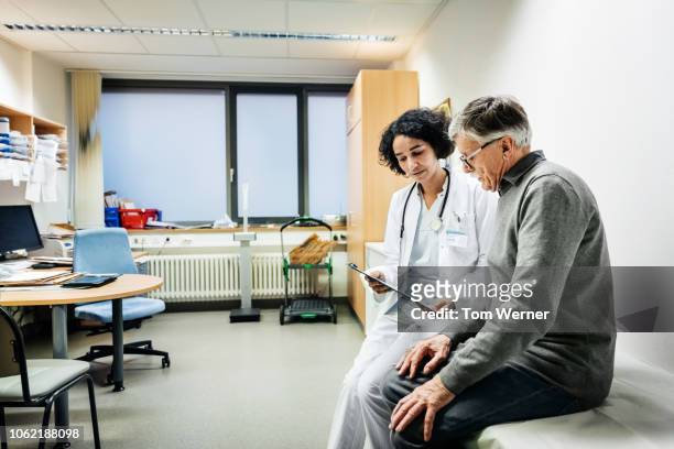 elderly man talking to doctor about test results - woman doctor stockfoto's en -beelden