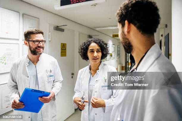 three doctors discussing patient information - diversity team clinic stock pictures, royalty-free photos & images