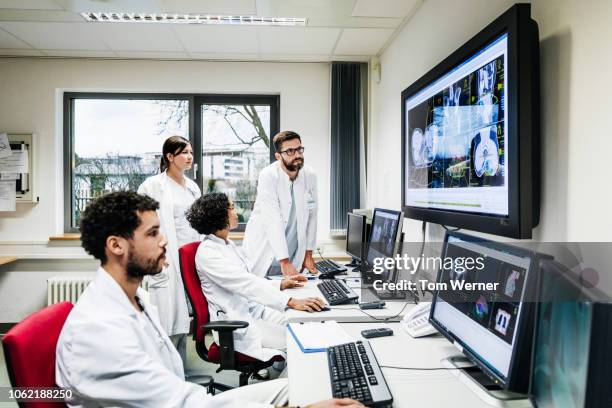 group of research doctors looking at patient data - outil de diagnostic médical photos et images de collection