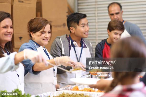 multi-ethnic group of volunteers serves food at soup kitchen. - service of thanksgiving stock pictures, royalty-free photos & images