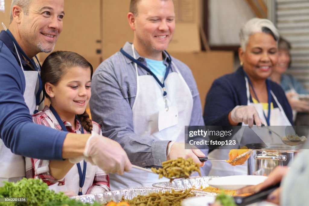 Multi-ethnic group of volunteers serves food at soup kitchen.