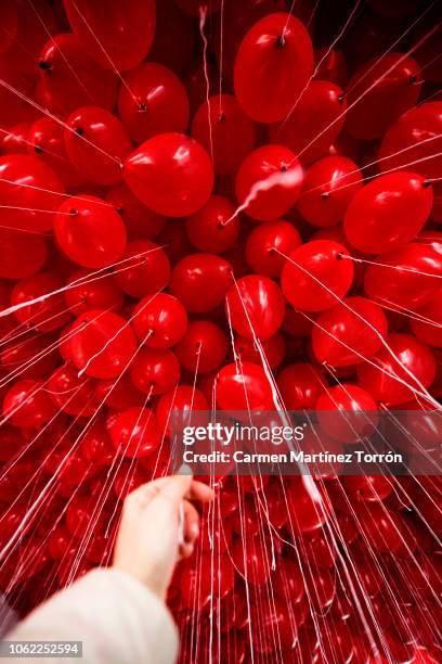 full frame shot of red helium balloons against ceiling in a coruña, spain. - blowing up balloon stock-fotos und bilder