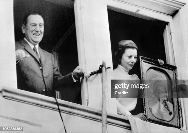 Former Argentinian president Juan Peron waves to the crowd while his wife Isabel Peron is presenting a portrait of Evita Peron from the balcony of...