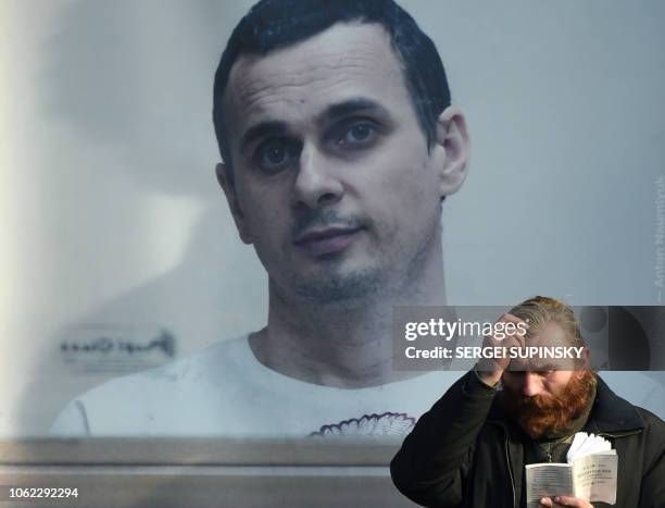 Man crosses himself in the center of Ukrainian capital of Kiev on November 16, 2018 as he prays at the placard depicting Ukrainian film director Oleg...