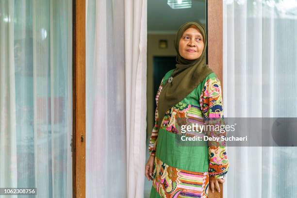possitive and confident muslim woman wearing colorful cloths standing by the door at home